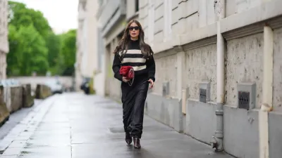 PARIS, FRANCE - APRIL 27: Heart Evangelista wears sunglasses, a black and white striped ribbed turtleneck pullover with golden buttons on the shoulders, a red fluffy Chanel bag, a black satin silky lustrous flowing skirt , brown pointed boots, during a street style fashion photo session, on April 27, 2024 in Paris, France. (Photo by Edward Berthelot/Getty Images)