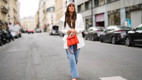 PARIS, FRANCE - APRIL 30: Tamara Kalinic wears a white Celine cap, a white latte ribs tank top, a gold chain pendant necklace, a white long Saint Laurent YSL blazer jacket, a white embroidered Chanel sweater, a red shiny leather Kelly Hermes handbag, blue faded denim boyfriend jeans Margiela pants, red and white shiny leather Nike Air Force 1 sneakers, on April 30, 2021 in Paris, France. (Photo by Edward Berthelot/Getty Images)