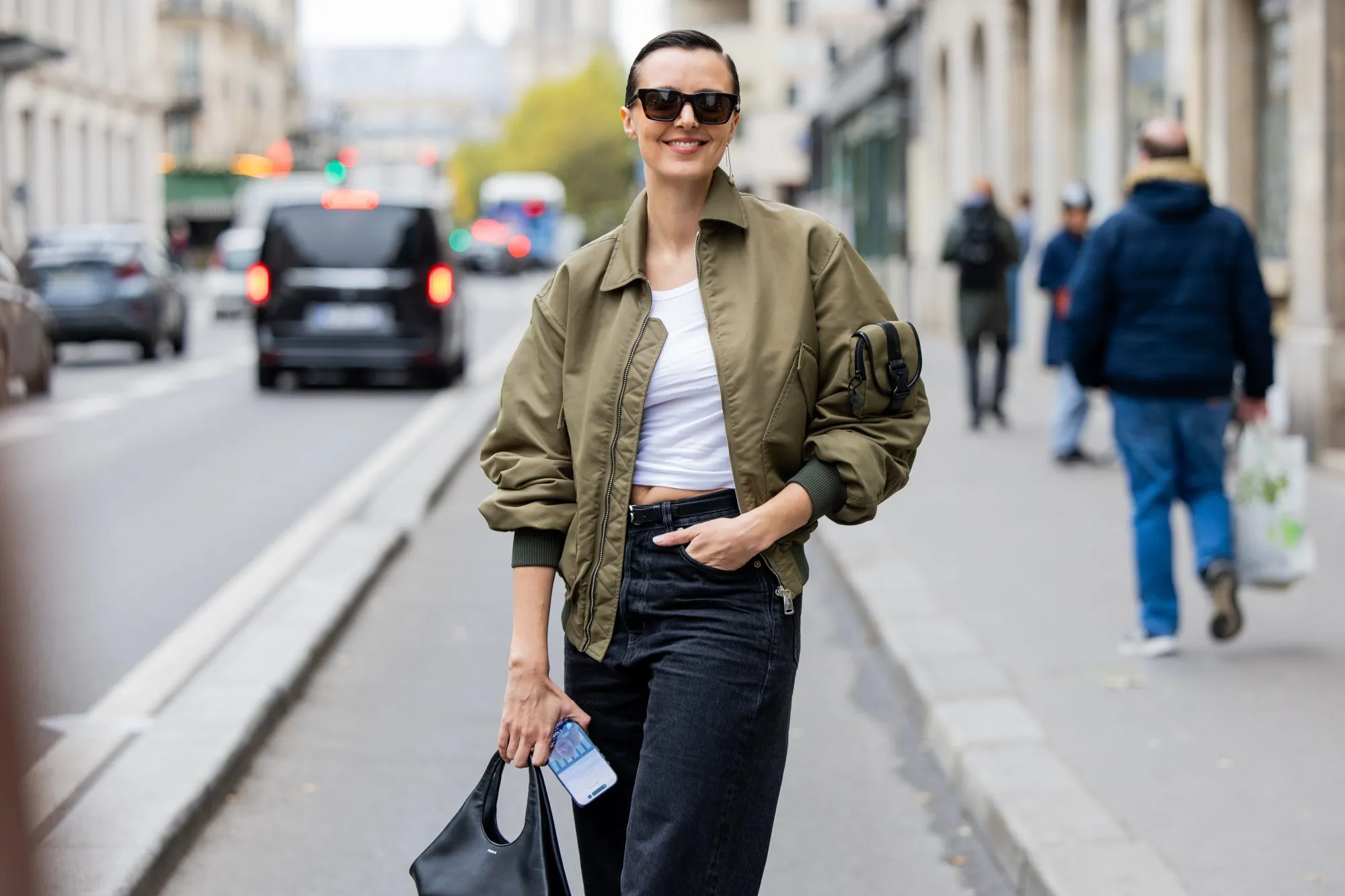 PARIS, FRANCE - OCTOBER 06: Jessie Inchauspé wears an olive green bomber jacket over a white crop top and high-waisted black jeans, accessorized with black sunglasses, brown pointed heels, and a small black bag outside Coperni during the Womenswear Spring Summer 2026 as part of Paris Fashion Week on October 06, 2025 in Paris, France. (Photo by Christian Vierig/Getty Images)