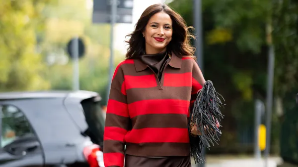 MILAN, ITALY - OCTOBER 14: Mariana Rodrigue arrives at the Veronica Marucci Chapeaux Lunch event "Ribot Chapeau" at Ribot Restaurant wearing a brown silk midi dress, leopard printed heels, a grey bag with fringes, a brown and red polo sweater and gold earrings on October 14, 2025 in Milan, Italy. (Photo by Valentina Frugiuele/Getty Images)
