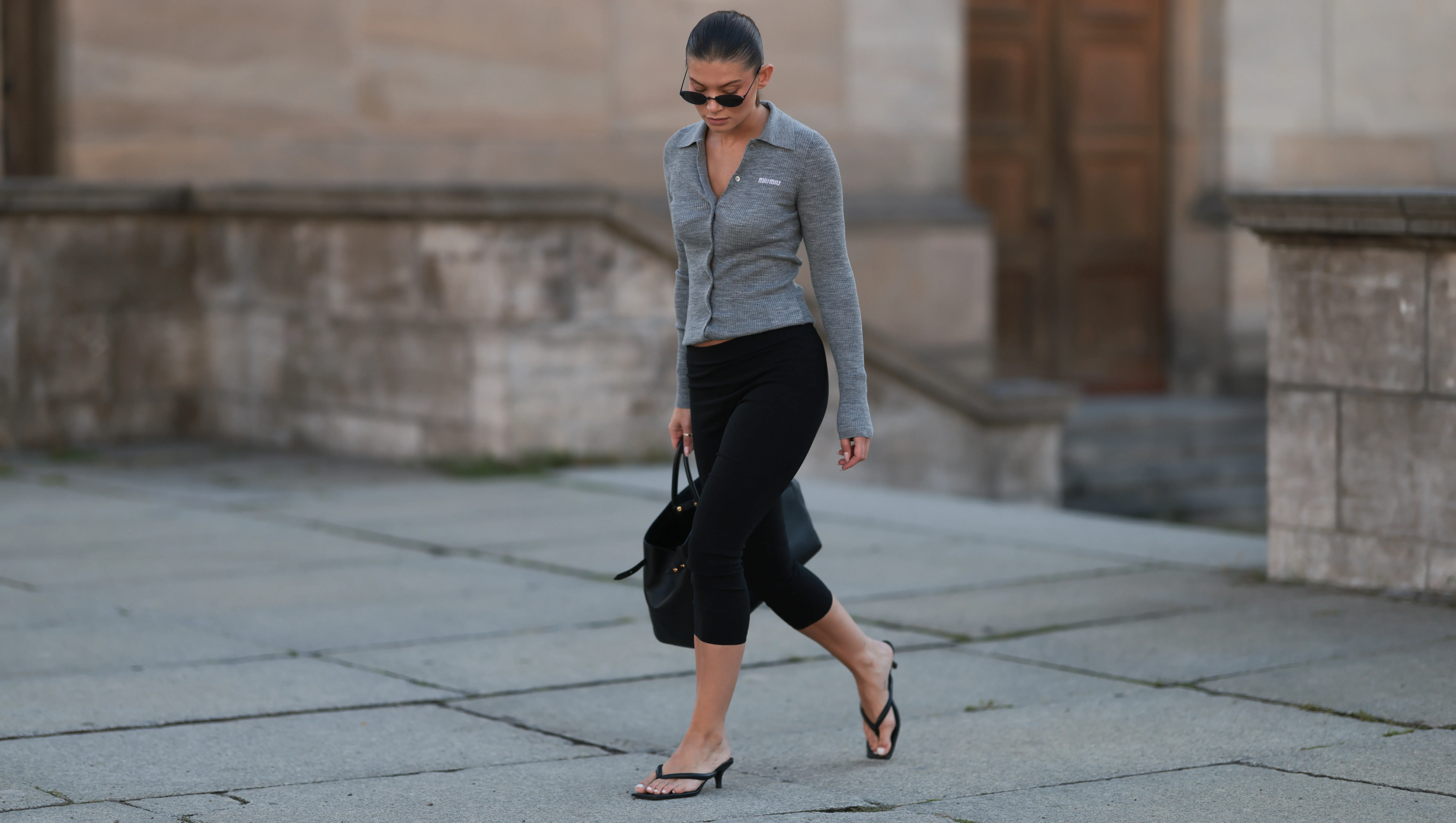 BERLIN, GERMANY - SEPTEMBER 06: Sophia Geiss seen wearing Vehla Eyewear narrow oval-shaped black sunglasses with sleek frames, Miu Miu fitted heather-grey ribbed cardigan top featuring a pointed collar and button-down front, Mango high-waisted black cropped leggings, Demelier London large structured black tote bag with gold hardware, LeGer black thong-strap heeled sandals / heels, on September 06, 2025 in Berlin, Germany. (Photo by Jeremy Moeller/Getty Images)
