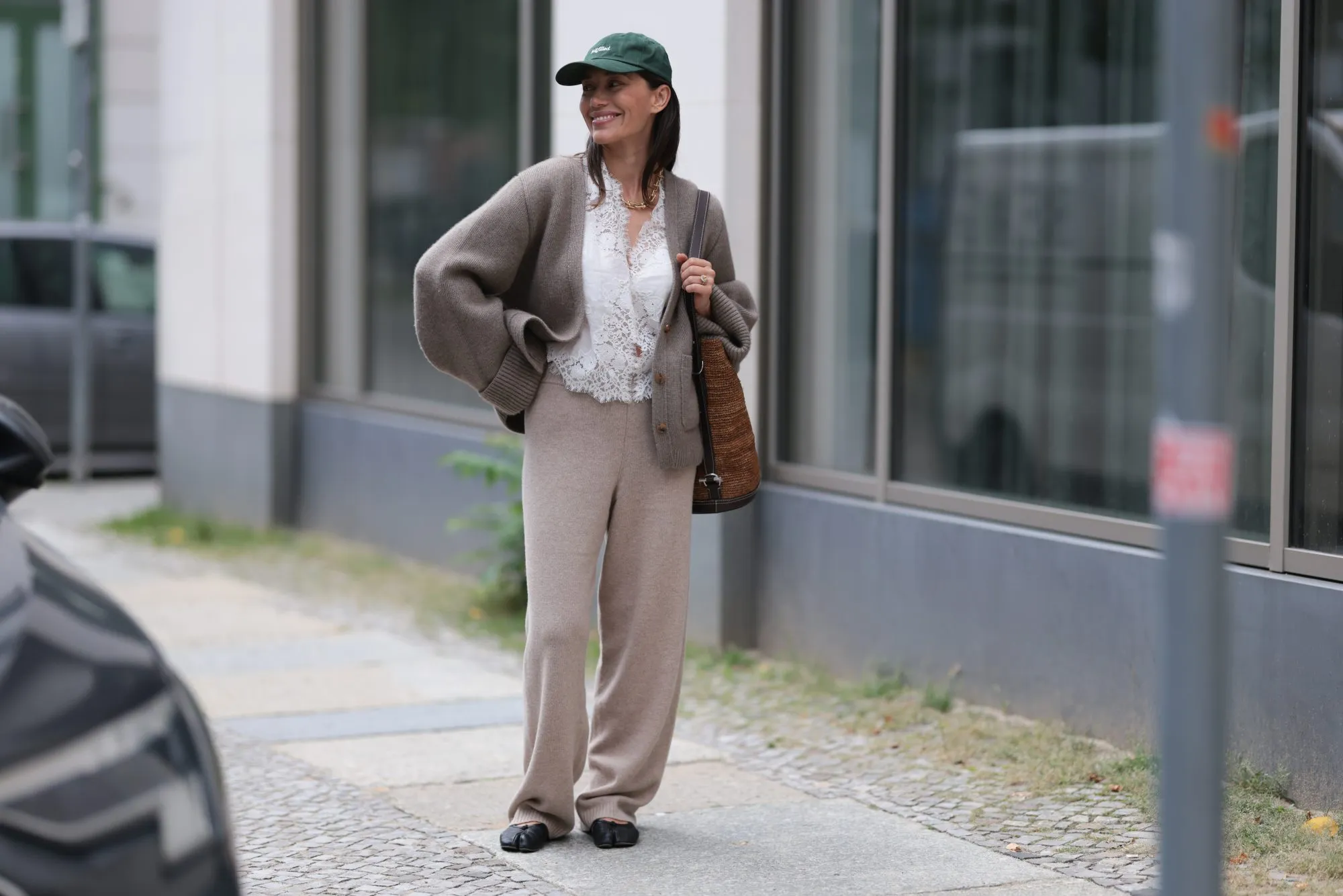 BERLIN, GERMANY - SEPTEMBER 16: Anna Schürrle seen wearing a dark green Fulfilled baseball cap with subtle white embroidery on the front. Her hair is left down, tucked naturally beneath the cap, giving the look an effortless and relaxed vibe. Around her neck, she accessorizes with a bold Tiffany & Co. City HardWear chunky, modern chain necklace in yellow gold, DÔEN white lace top, semi-sheer with intricate embroidery and scalloped hems, over it, she wears a Khaite knit cardigan in a soft taupe tone. The cardigan is oversized with rolled-up cuffs, By Aylin Koenig relaxed, wide-leg knit pants in a soft beige tone. The drape is fluid and comfortable, balancing elegance with loungewear appeal. Polo Ralph Lauren woven tote bag, crafted from natural fibers in a warm brown tone, with the iconic Polo player logo in black leather and Maison Margiela black leather Tabi ballet flats, on September 16, 2025 in Berlin, Germany. (Photo by Jeremy Moeller/Getty Images)