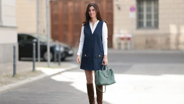 BERLIN, GERMANY - AUGUST 24: Leo Eberlin seen wearing Leo Mathild diamond jewelry / yellow gold necklace, white gold diamond rings, Leo Mathild white / yellow gold diamond bracelets, Audemars Piguet Royal Oak yellow gold vintage watch, Arket white long-sleeve cotton blouse featuring a sharp collar, layered underneath a Frame dark blue sleeveless denim mini dress structured patch pockets with gold button details, Bottega Veneta Andiamo woven sage green leather bag and Saint Laurent brown suede leather knee-high heeled boots, on August 24, 2025 in Berlin, Germany. (Photo by Jeremy Moeller/Getty Images)