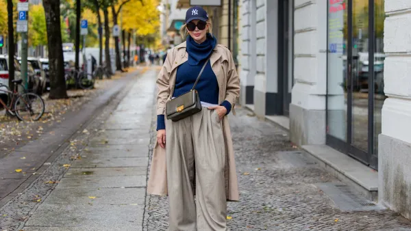 A woman walking in the cirt wearing Fall Trousers and a long jacket.