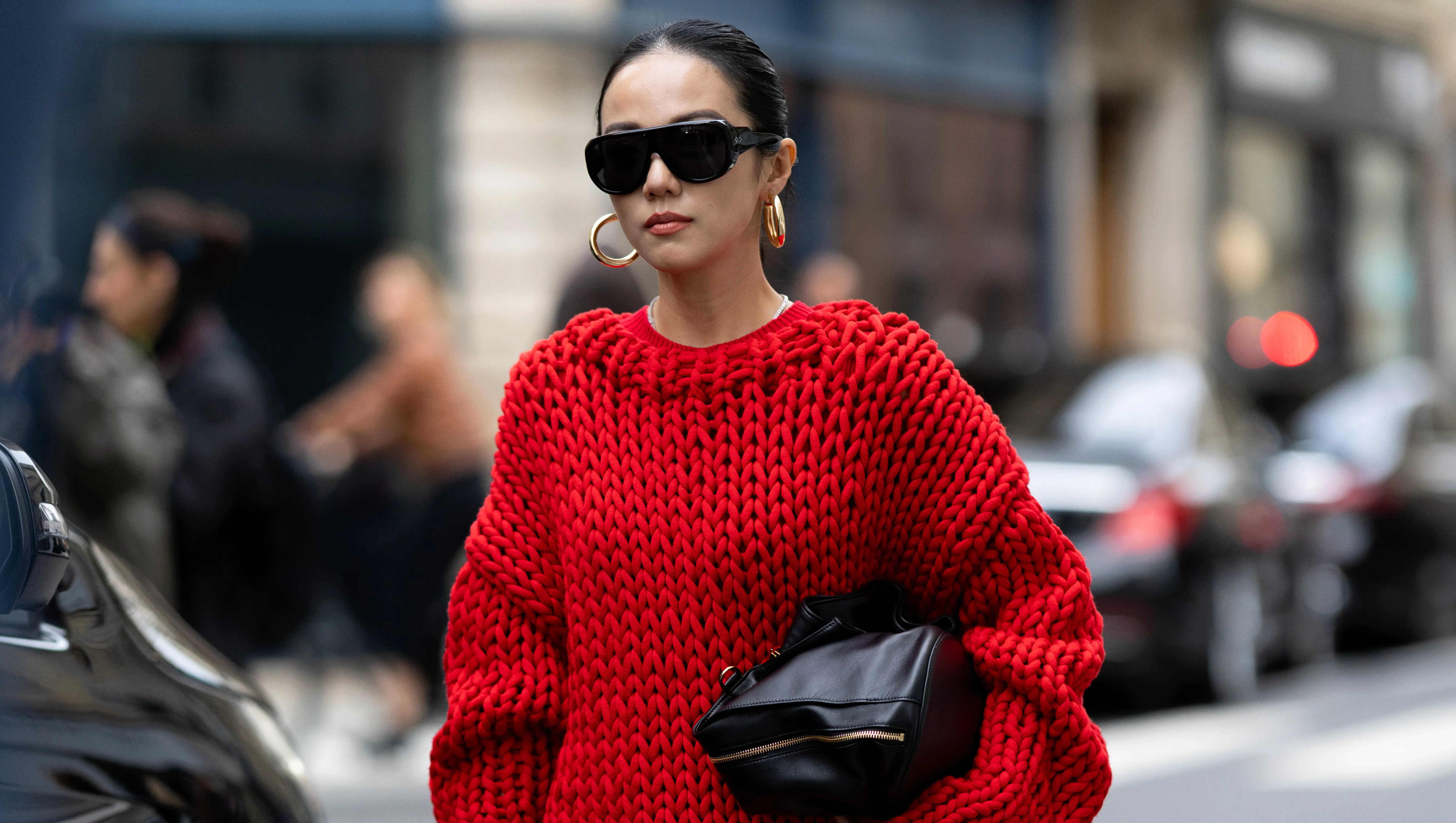 PARIS, FRANCE - OCTOBER 06: Yoyo Cao wears an oversized chunky red knit sweater with a matching red mini skirt, black knee-high heeled boots, black oversized sunglasses, and gold hoop earrings, carrying a black clutch outside Sacai show during the Womenswear Spring Summer 2026 as part of Paris Fashion Week on October 06, 2025 in Paris, France. (Photo by Valentina Frugiuele/Getty Images)
