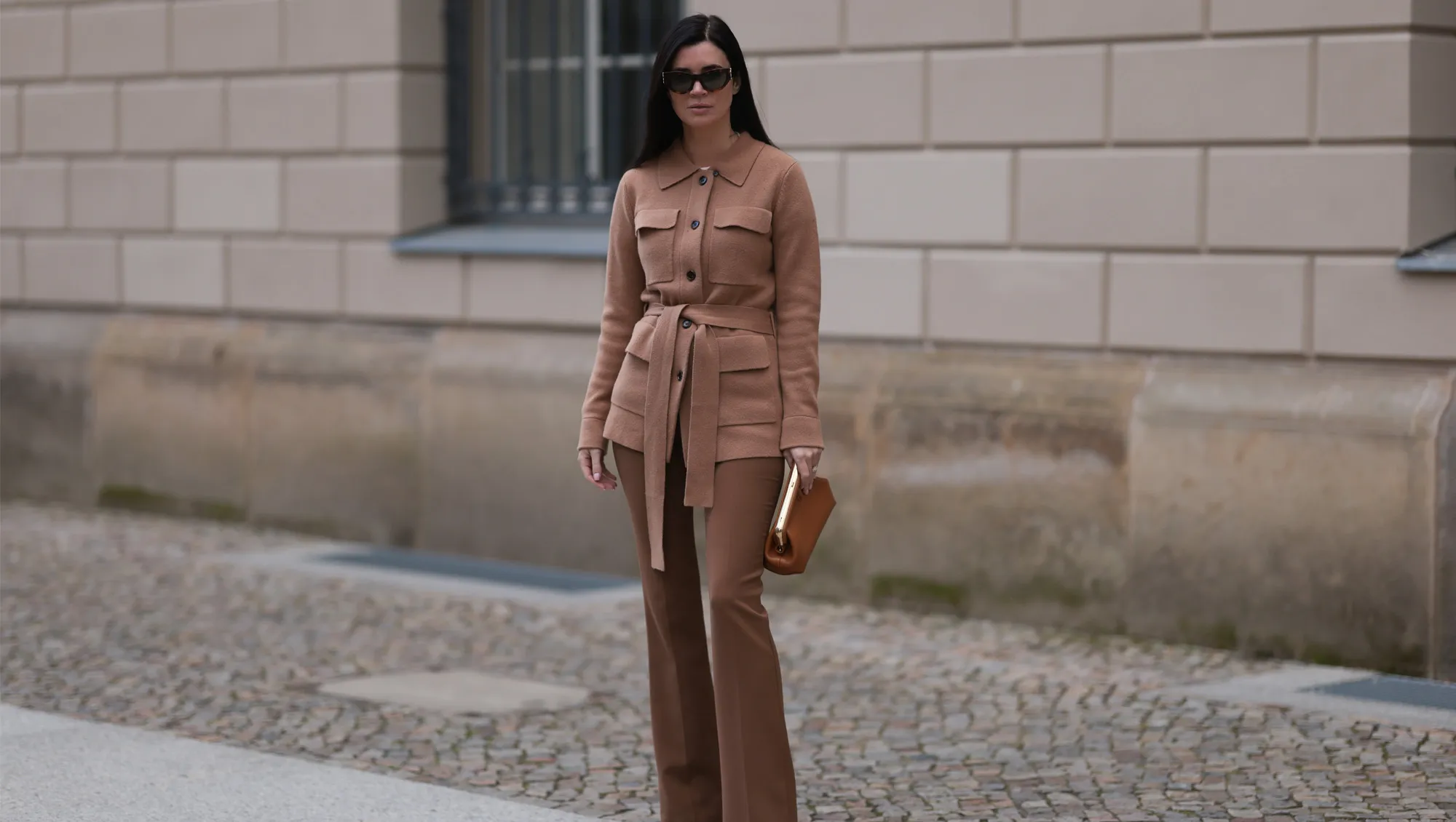 Leo Eberlin seen wearing YSL brown tortoise sunglasses, Leo Mathild diamond jewelry, Allude x Leo Mathild brown cashmere wool cardigan jacket, Zara brown suit pants, Fendi brown leather clutch / pouch bag and Christian Louboutin brown leather heels / pumps, on February 25, 2024 in Berlin, Germany.