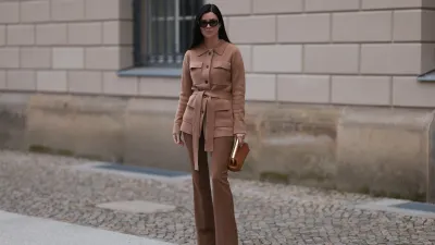 Leo Eberlin seen wearing YSL brown tortoise sunglasses, Leo Mathild diamond jewelry, Allude x Leo Mathild brown cashmere wool cardigan jacket, Zara brown suit pants, Fendi brown leather clutch / pouch bag and Christian Louboutin brown leather heels / pumps, on February 25, 2024 in Berlin, Germany.
