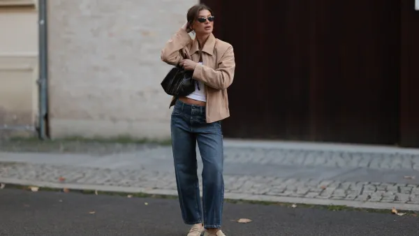 BERLIN, GERMANY - SEPTEMBER 06: Sophia Geiss seen wearing Vehla Eyewear narrow oval-shaped black sunglasses with sleek frames, crisp white scoop-neck cotton basic tank top, The Worn cropped beige suede vintage jacket with a structured collar and relaxed sleeves, Cambio straight-leg mid-wash slightly loose denim jeans, The Frankie Shop black small leather drawstring bag with a glossy finish and Camper beige suede leather loafers, on September 06, 2025 in Berlin, Germany. (Photo by Jeremy Moeller/Getty Images)