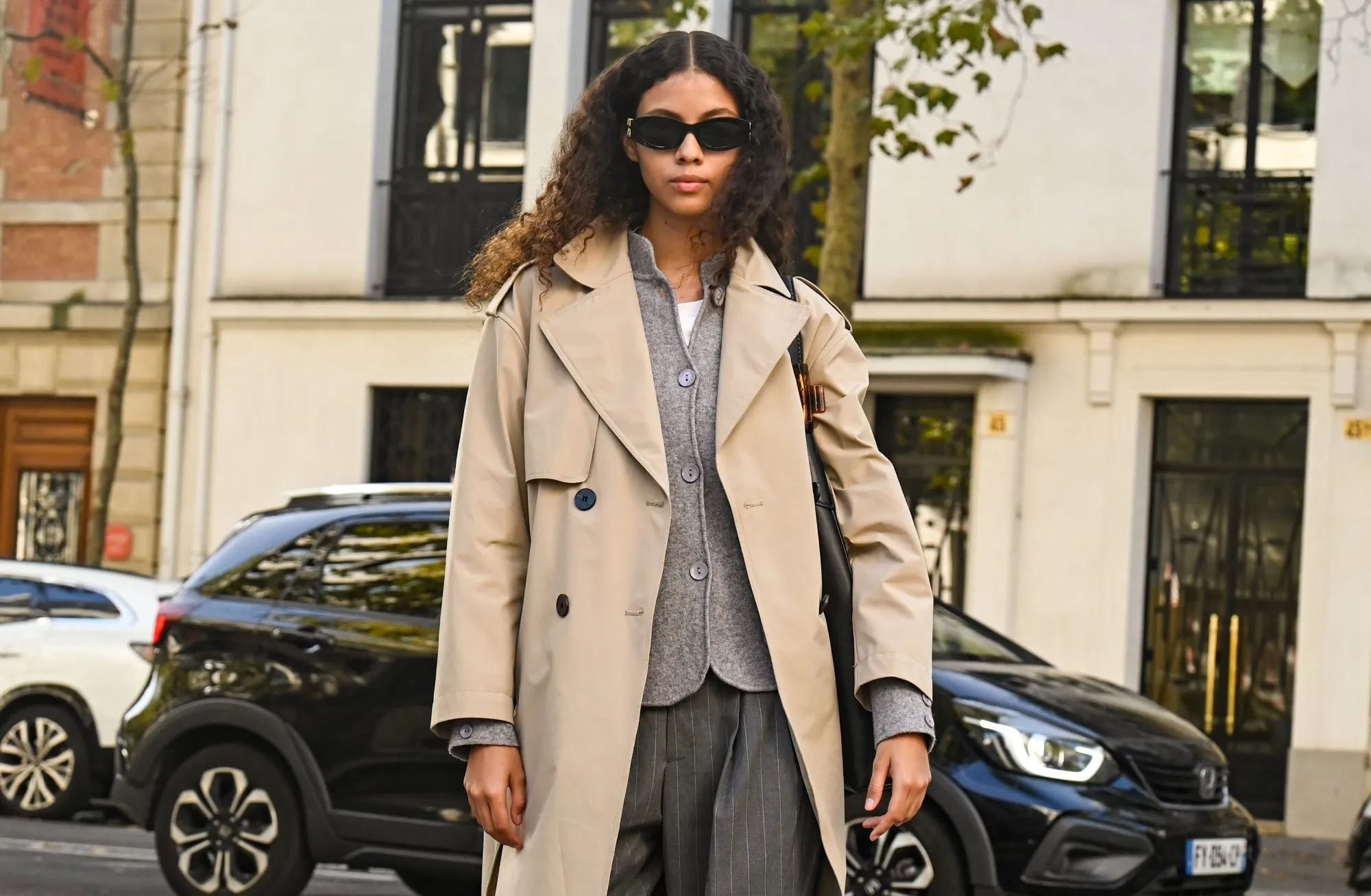 PARIS, FRANCE - OCTOBER 05: Model Nazarit Machin is seen wearing a tan trench coat, gray cardigan, gray pants, shoes and black sunglasses with black bag outside the Lacoste show during the Womenswear Spring Summer 2026 as part of Paris Fashion Week on October 05, 2025 in Paris, France. (Photo by Daniel Zuchnik/Getty Images)