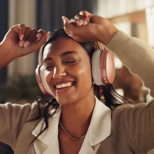Woman dancing while wearing over-ear headphones similar to Apple AirPods Max during Black Friday sale.