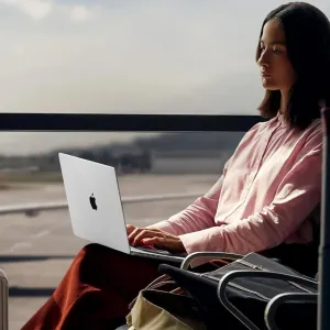 Woman using a MacBook at the airport during travel