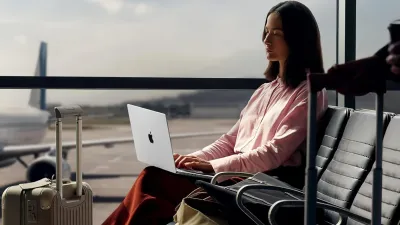 Woman using a MacBook at the airport during travel