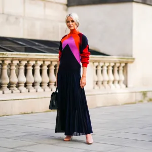 Victoria Magrath wears an orange red and pink wool pullover with a turtleneck, a black lace pleated skirt, a black leather bag, during London Fashion Week September 2019 on September 15, 2019 in London, England.