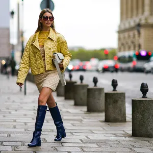PARIS, FRANCE - SEPTEMBER 28: Natalia Verza wears sunglasses, a Fendi full outfit made of a yellow padded silky jacket, a Fendi leather monogram bag, a beige padded dress with yellow ruffled mesh upper part, blue leather Fendi long boots, on September 28, 2020 in Paris, France. (Photo by Edward Berthelot/Getty Images)