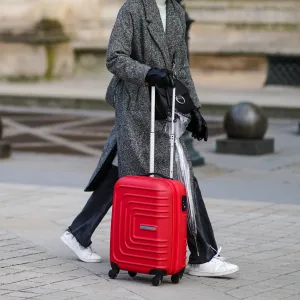 PARIS, FRANCE - JANUARY 17: A passerby wears a white woven turtleneck wool pullover, a gray oversized long coat, black denim jeans ripped pants, white leather laces sneakers, black shiny leather gloves, a black shiny leather crossbody bag, a transparent umbrella, a red large suitcase, on January 17, 2021 in Paris, France. (Photo by Edward Berthelot/Getty Images)