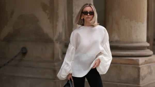 HAMBURG, GERMANY - APRIL 05: Isabelle Hartmann seen wearing Vehla Eyewear black / brown sunglasses, Nootka gold earrings, Khaite oversized puffy ruffled long sleeve silk top, Isabelle Hartmann x Edited black slit pants and Toteme black leather bag on April 05, 2024 in Hamburg, Germany. (Photo by Jeremy Moeller/Getty Images)