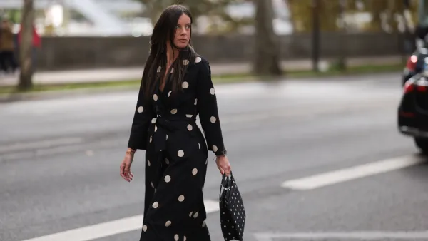 A Fashion Week guest is seen wearing round diamond stud earrings; a long-sleeved black midi dress with white polka dot pattern, notched lapels, and a tie belt; a gold bangle; a rose gold and black watch from Rolex; a gold ring; and a rectangular black handbag with a white polka dot pattern before the Elie Saab Womenswear Spring/Summer 2025 Show as part of Paris Fashion Week on September 28, 2024 in Paris, France.