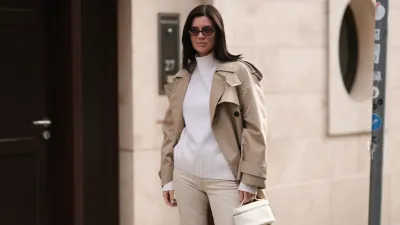 Leo Eberlin is seen wearing oval sunglasses with dark Havana frame and pink lenses and a gold logo at the temples from Miu Miu, a calf-length beige trench coat with double button placket and large notch lapels from Zara, a white cashmere turtleneck pullover with ribbed trims from Allude, beige jeans from Khaite, a diamond ring from Leo Mathild, and a rectangular small white leather bag from Loro Piana on October 03, 2024 in Berlin, Germany.