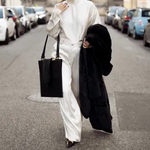 Gili Biegun wears silk cream long trousers and matching top with neck detail by Aeron, black leather square bag by Aeron, long black leather gloves, extra large faux fur coat and Saint Laurent heels on December 03, 2024 in Copenhagen, Denmark.