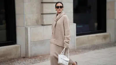 Laura Noltemeyer is seen wearing an oversized beige alpaca wool sweater with tie-back detailing by Aylin König; a long alpaca wool knit skirt in a straight cut by Aylin König; an alpaca knit scarf draped and knotted around the neck by Aylin König; a white intrecciato leather handbag called „Arco Bag“ by Bottega Veneta; slim black cat-eye sunglasses by Yves Saint Laurent; gold statement earrings with a green stone detail by Mango; her brown and straight hair is tied in a low ponytail on October 16, 2025 in Hamburg, Germany.