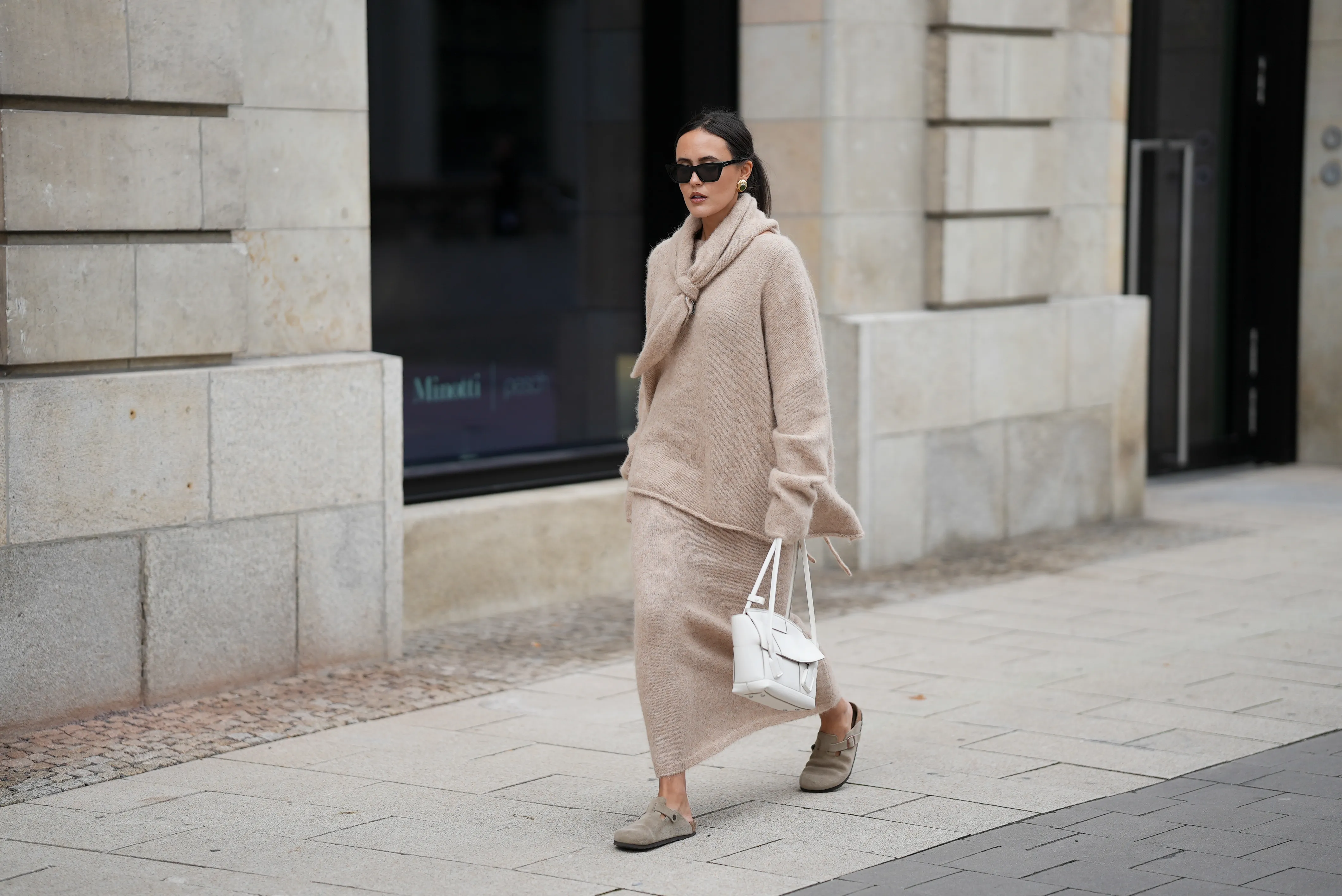 Laura Noltemeyer is seen wearing an oversized beige alpaca wool sweater with tie-back detailing by Aylin K&ouml;nig; a long alpaca wool knit skirt in a straight cut by Aylin K&ouml;nig; an alpaca knit scarf draped and knotted around the neck by Aylin K&ouml;nig; beige suede Boston clogs by Birkenstock; a white intrecciato leather handbag called &bdquo;Arco Bag&ldquo; by Bottega Veneta; slim black cat-eye sunglasses by Yves Saint Laurent; gold statement earrings with a green stone detail by Mango; her brown and straight hair is tied in a low ponytail on October 16, 2025 in Hamburg, Germany.