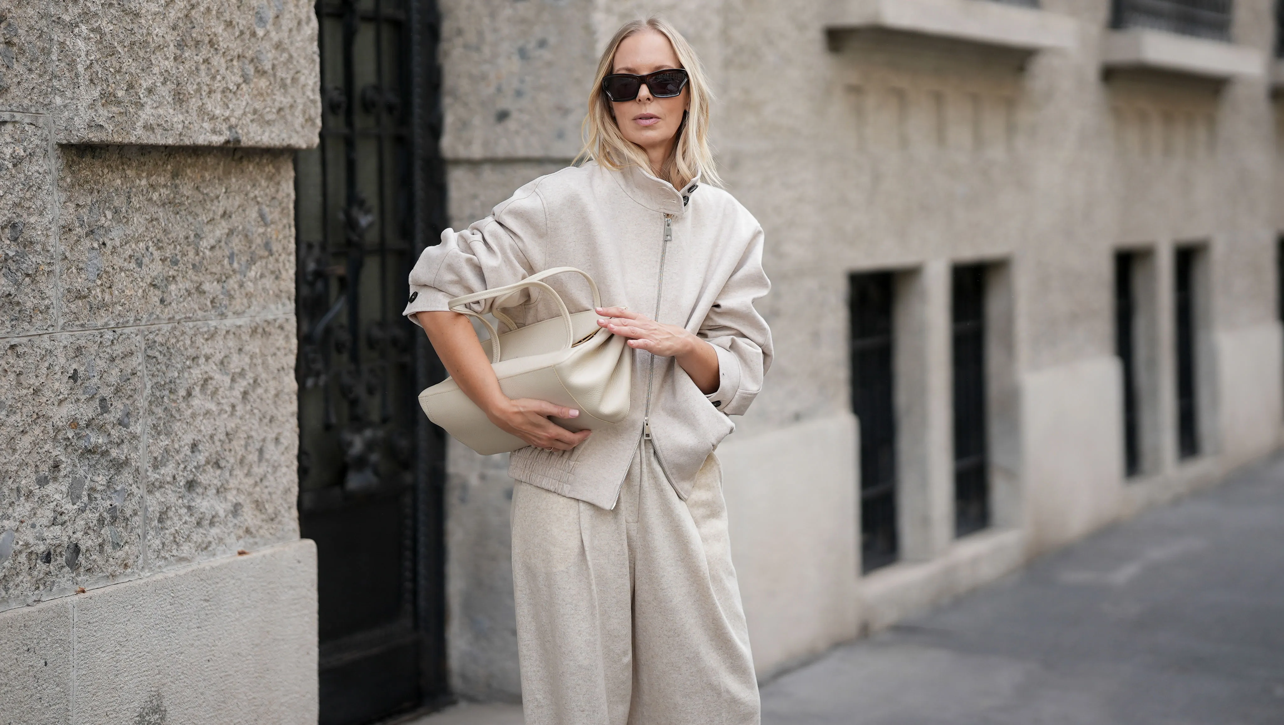 MILAN, ITALY - SEPTEMBER 25: Mirja Klein is seen wearing a beige wool zip-up bomber jacket with a high collar and elastic waistband by Liviana Conti; beige wide-leg wool trousers in a relaxed silhouette by Liviana Conti; an off-white structured leather handbag with top handles and a flap top by Liviana Conti; rectangular black sunglasses with a glossy acetate frame by Loewe; her blond hair is worn loose with a middle parting on September 25, 2025 in Milan, Italy. (Photo by Moritz Scholz/Getty Images)