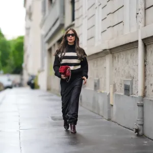 PARIS, FRANCE - APRIL 27: Heart Evangelista wears sunglasses, a black and white striped ribbed turtleneck pullover with golden buttons on the shoulders, a red fluffy Chanel bag, a black satin silky lustrous flowing skirt , brown pointed boots, during a street style fashion photo session, on April 27, 2024 in Paris, France. (Photo by Edward Berthelot/Getty Images)
