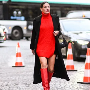 PARIS, FRANCE - SEPTEMBER 29: A guest is seen wearing a black coat, red dress, red knee high boots and black Prada bag outside the Isabel Marant show during Womenswear Spring/Summer2025 as part of Paris Fashion Week on September 29, 2024 in Paris, France. (Photo by Daniel Zuchnik/Getty Images)