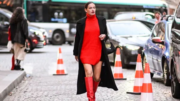 PARIS, FRANCE - SEPTEMBER 29: A guest is seen wearing a black coat, red dress, red knee high boots and black Prada bag outside the Isabel Marant show during Womenswear Spring/Summer2025 as part of Paris Fashion Week on September 29, 2024 in Paris, France. (Photo by Daniel Zuchnik/Getty Images)