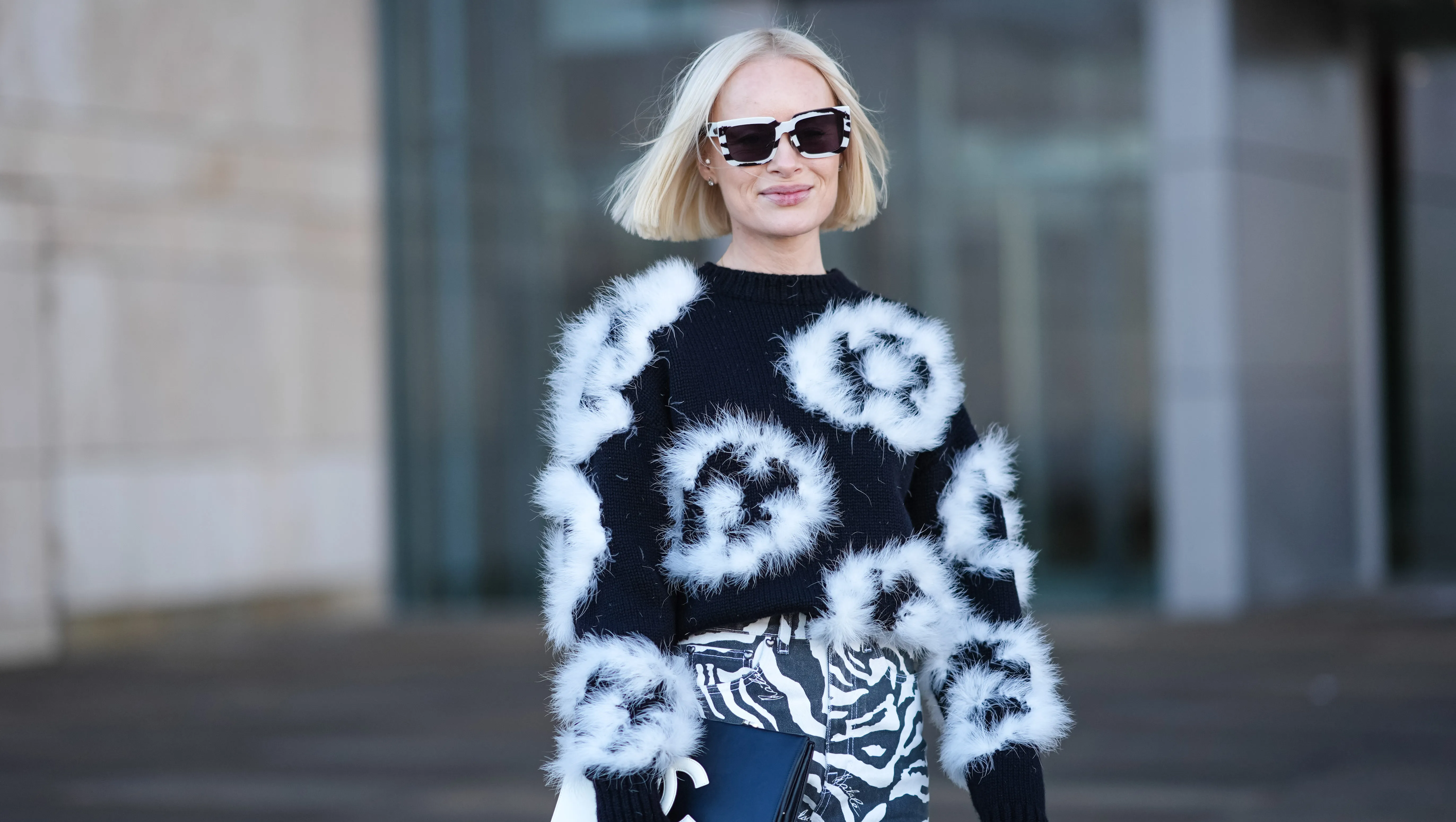 COPENHAGEN, DENMARK - JANUARY 31: Thora Valdimars wears a black and white full look, sunglasses, a floral print fluffy pullover , striped zebra print pants,, a Chanel bi-color clutch, outside OperaSport, during the Copenhagen Fashion Week AW24 on January 31, 2024 in Copenhagen, Denmark. (Photo by Edward Berthelot/Getty Images)