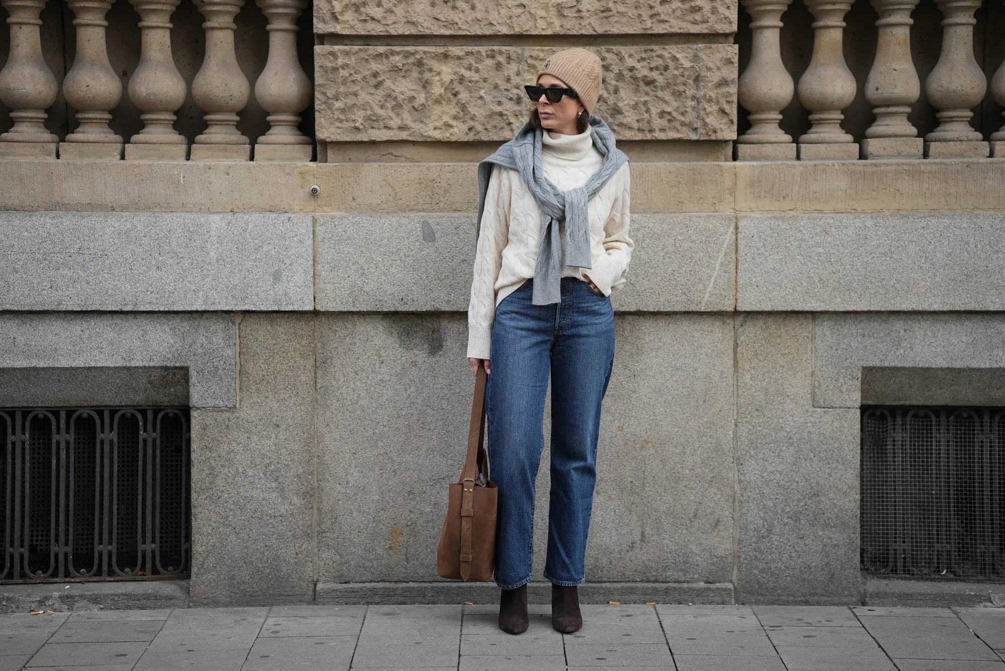 DUESSELDORF, GERMANY - NOVEMBER 10: Patricia Wirschke is seen wearing a cream cable-knit turtleneck sweater by Tommy Hilfiger; a light grey cable-knit sweater draped over her shoulders by Tommy Hilfiger; straight-leg blue jeans by Levi’s; brown suede boots with a pointed toe by Massimo Dutti; a brown suede tote bag with a shoulder strap by Max Mara; black cat-eye sunglasses by Phoebe Philo; a beige ribbed beanie with an embroidered crest logo by Tommy Hilfiger; her brown hair is worn straight and tucked into the collar; gold “Serpenti” earrings by Bulgari on November 10, 2025 in Duesseldorf, Germany. (Photo by Moritz Scholz/Getty Images)