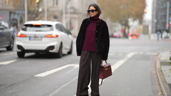 DUESSELDORF, GERMANY - NOVEMBER 10: Patricia Wirschke is seen wearing a dark brown shearling jacket with a boxy cut by Manzoni 24; a burgundy cashmere turtleneck sweater by Van Kukil; wide-leg tailored trousers in dark brown wool by Seductive; brown suede loafers with ruffled stitching by Yves Saint Laurent; a structured burgundy leather “Kelly 25” handbag with gold hardware in Rouge H by Hermès; black cat-eye sunglasses by Phoebe Philo; her brown hair is straight with a center parting and tucked into the collar on November 10, 2025 in Duesseldorf, Germany. (Photo by Moritz Scholz/Getty Images)