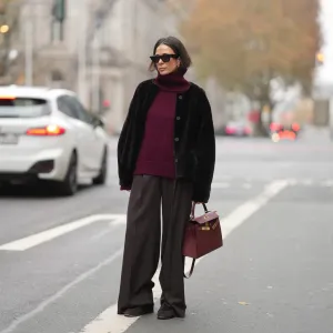 DUESSELDORF, GERMANY - NOVEMBER 10: Patricia Wirschke is seen wearing a dark brown shearling jacket with a boxy cut by Manzoni 24; a burgundy cashmere turtleneck sweater by Van Kukil; wide-leg tailored trousers in dark brown wool by Seductive; brown suede loafers with ruffled stitching by Yves Saint Laurent; a structured burgundy leather “Kelly 25” handbag with gold hardware in Rouge H by Hermès; black cat-eye sunglasses by Phoebe Philo; her brown hair is straight with a center parting and tucked into the collar on November 10, 2025 in Duesseldorf, Germany. (Photo by Moritz Scholz/Getty Images)