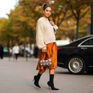 PARIS, FRANCE - SEPTEMBER 28: Tamara Kalinic wears a wool pullover, an orange shiny silky skirt, earrings, a Fendi bag, black high heeled boots, outside CDG Comme des Garçons, during Paris Fashion Week - Womenswear Spring Summer 2020 on September 28, 2019 in Paris, France. (Photo by Edward Berthelot/Getty Images)