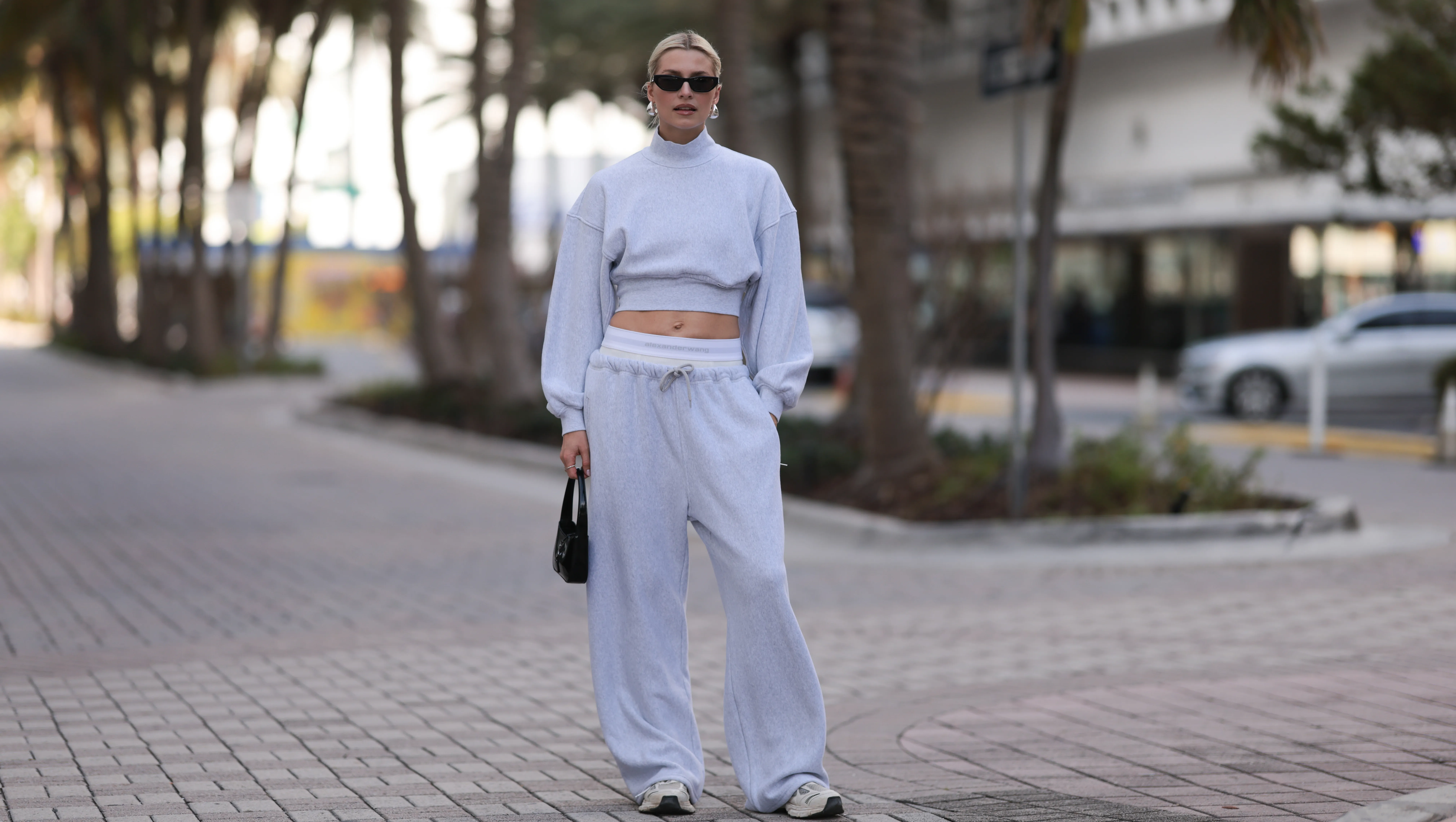 MIAMI, FLORIDA - DECEMBER 08: Lena Gercke seen wearing Saint Laurent black sunglasses, silver statement necklace, Alexander Wang light grey high neck cotton cropped jumper / sweater, Alexander Wang light grey cotton wide leg jogger pants with underwear detail, Saint Laurent black varnishes leather mini bag and Axel Arigato white leather sneakers, on December 08, 2023 in Miami, Florida. (Photo by Jeremy Moeller/Getty Images)2