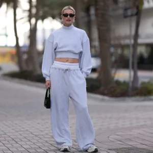 MIAMI, FLORIDA - DECEMBER 08: Lena Gercke seen wearing Saint Laurent black sunglasses, silver statement necklace, Alexander Wang light grey high neck cotton cropped jumper / sweater, Alexander Wang light grey cotton wide leg jogger pants with underwear detail, Saint Laurent black varnishes leather mini bag and Axel Arigato white leather sneakers, on December 08, 2023 in Miami, Florida. (Photo by Jeremy Moeller/Getty Images)2