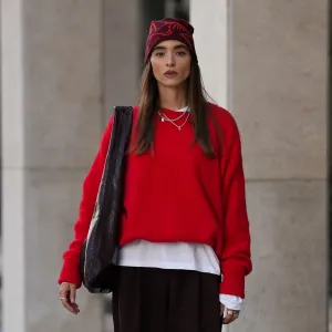 COLOGNE, GERMANY - SEPTEMBER 18: Evi Wave is seen wearing a bright red knit sweater with long sleeves from American Vintage; a white long-sleeved t-shirt, worn under the sweater from Weekday; wide-leg, brown trousers with a voluminous silhouette from COS; brown leather loafers with a subtle shine from Vagabond; a large bordeaux leather shoulder bag with a glossy shade from Arket; subtle silver jewellry, featuring metallic necklaces and rings from Ariane Ernst; a red patterned beanie from ArcTeryx; her brown hair is worn loose on September 18, 2025 in Cologne, Germany. (Photo by Moritz Scholz/Getty Images)