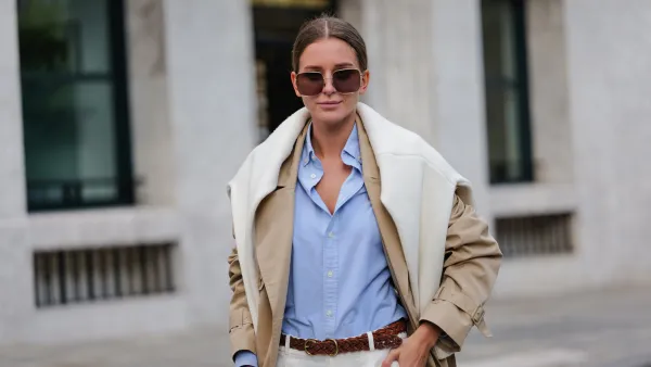 PARIS, FRANCE - APRIL 21: Diane Batoukina wears dark brown squared sunglasses from Dior, a pale blue cotton shirt from Ralph Lauren, a white matte large cashmere pullover from Weekend & Beyond, a beige oversized long trench coat from Filippa K, a brown braided leather belt from Ralph Lauren, white linen large pants from Ralph Lauren, a camel brown shiny leather crocodile print pattern handbag from Ralph Lauren, during a street style fashion photo session, on April 21, 2023 in Paris, France. (Photo by Edward Berthelot/Getty Images)