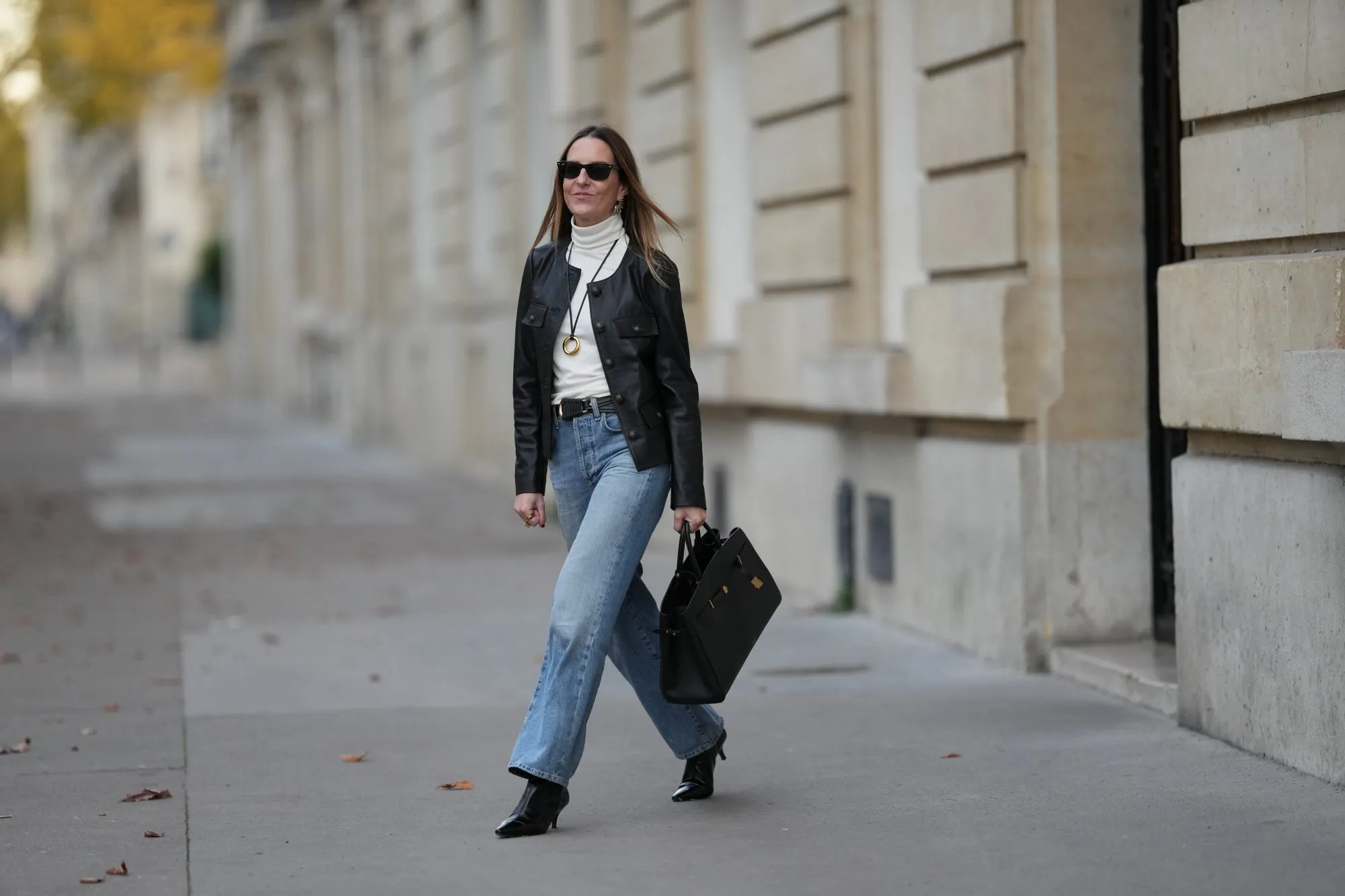 PARIS, FRANCE - NOVEMBER 05: Alba Garavito Torre wears long straight brown hair, a black leather jacket with gold buttons by Maison123, an ivory white turtleneck t-shirt by Maison123, light blue straight-leg jeans by Citizens of Humanity, black shiny leather pointed-toe high heel ankle boots by Jonak, a black leather bag by DeMellier London, and gold jewelry by Sempiterno Paris, during a street style fashion photo session, on November 05, 2025 in Paris, France. (Photo by Edward Berthelot/Getty Images)