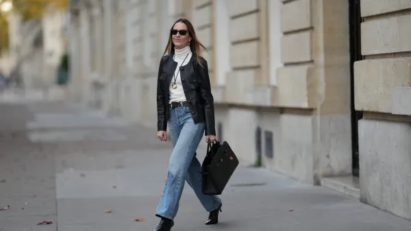 PARIS, FRANCE - NOVEMBER 05: Alba Garavito Torre wears long straight brown hair, a black leather jacket with gold buttons by Maison123, an ivory white turtleneck t-shirt by Maison123, light blue straight-leg jeans by Citizens of Humanity, black shiny leather pointed-toe high heel ankle boots by Jonak, a black leather bag by DeMellier London, and gold jewelry by Sempiterno Paris, during a street style fashion photo session, on November 05, 2025 in Paris, France. (Photo by Edward Berthelot/Getty Images)