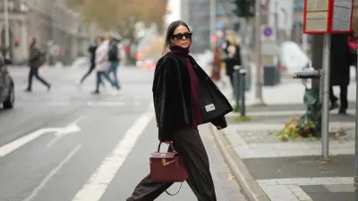 DUESSELDORF, GERMANY - NOVEMBER 10: Patricia Wirschke is seen wearing a dark brown shearling jacket with a boxy cut by Manzoni 24; a burgundy cashmere turtleneck sweater by Van Kukil; wide-leg tailored trousers in dark brown wool by Seductive; brown suede loafers with ruffled stitching by Yves Saint Laurent; a structured burgundy leather “Kelly 25” handbag with gold hardware in Rouge H by Hermès; black cat-eye sunglasses by Phoebe Philo; her brown hair is straight with a center parting and tucked into the collar on November 10, 2025 in Duesseldorf, Germany. (Photo by Moritz Scholz/Getty Images)