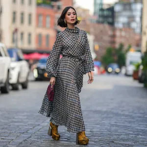 NEW YORK, NEW YORK - SEPTEMBER 12: Heart Evangelista wears golden earrings, a houndstooth pattern printed midi pleated dress, a burgundy leather bag from Carolina Herrera, golden floral print platform boots, outside Carolina Herrera, during New York Fashion Week, on September 12, 2023 in New York City. (Photo by Edward Berthelot/Getty Images)