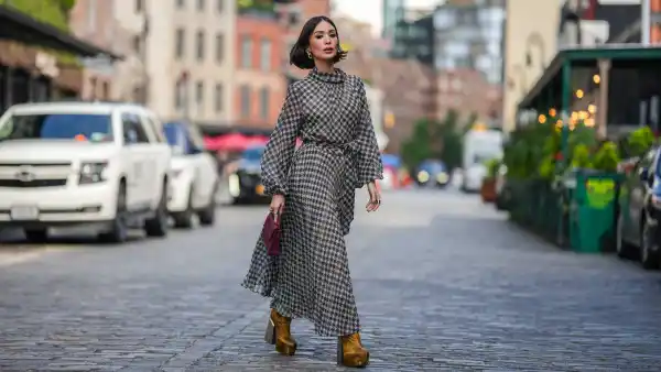NEW YORK, NEW YORK - SEPTEMBER 12: Heart Evangelista wears golden earrings, a houndstooth pattern printed midi pleated dress, a burgundy leather bag from Carolina Herrera, golden floral print platform boots, outside Carolina Herrera, during New York Fashion Week, on September 12, 2023 in New York City. (Photo by Edward Berthelot/Getty Images)