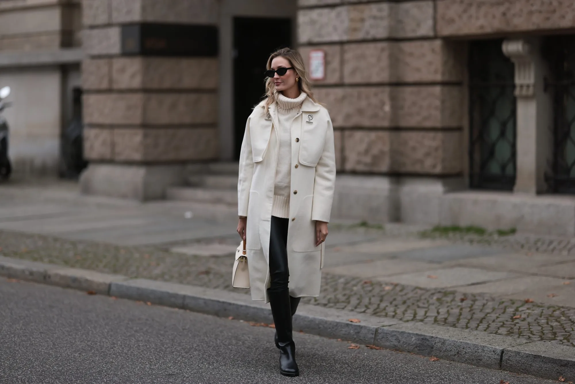 BERLIN, GERMANY - NOVEMBER 07: Mandy Bork wearing Chanel black leather boots, Chanel black round shades, Wolford black leather leggings, Hermes beige coat and Hermes beige leather Kelly bag and H&M knit turtleneck sweater on November 07, 2022 in Berlin, Germany. (Photo by Jeremy Moeller/Getty Images)
