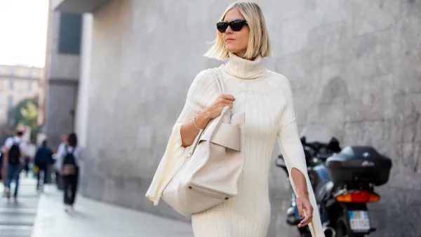 Linda Tol outside Max Mara fashion show wearing a knitted white dress, oversized white bag and sunglasses during the Milan Fashion Week - Spring / Summer 2022 on September 22, 2022 in Milan, Italy.