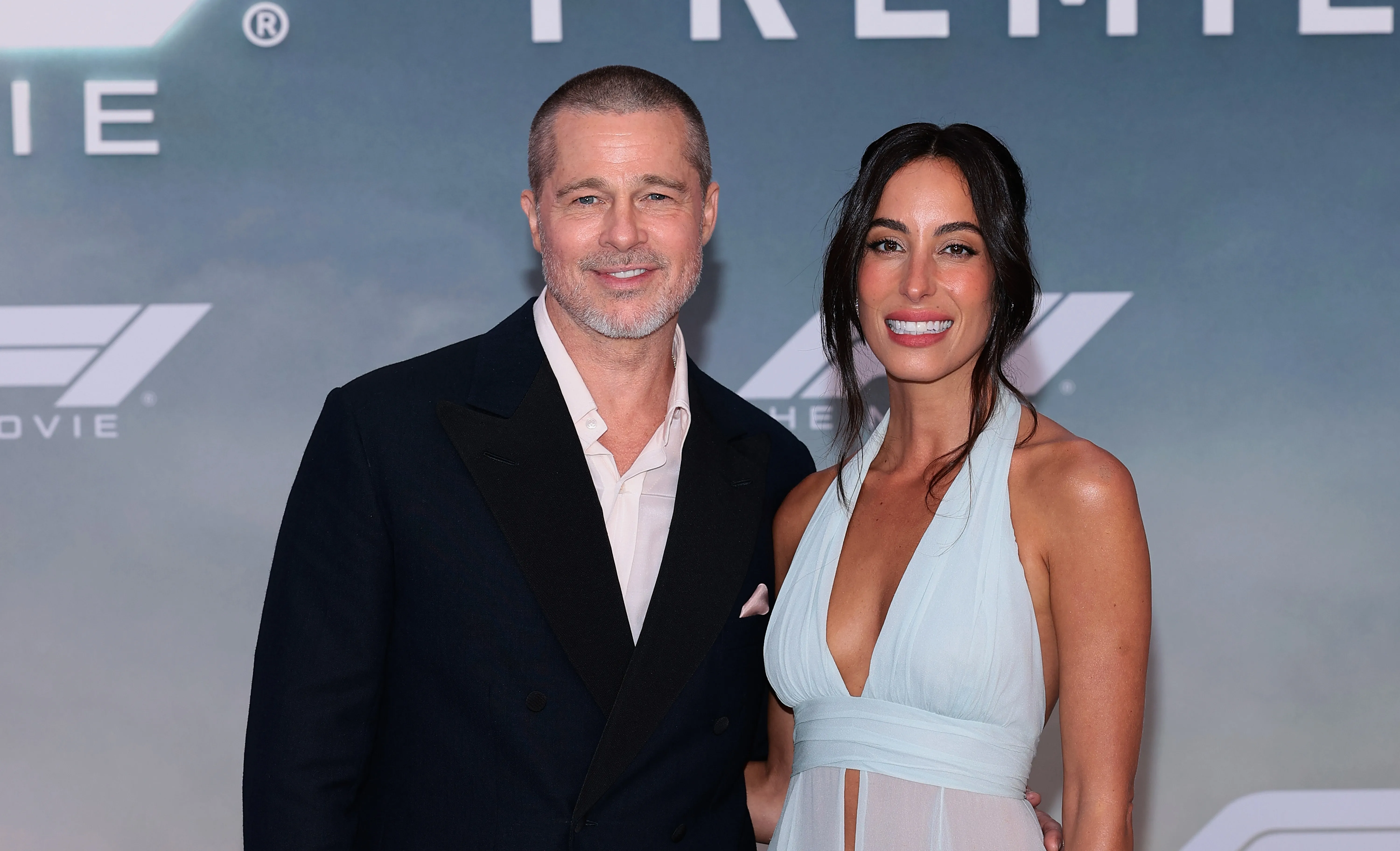 Brad Pitt and Ines de Ramon smiling together on the "F1" premiere red carpet.