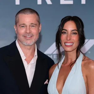 Brad Pitt and Ines de Ramon smiling together on the "F1" premiere red carpet.