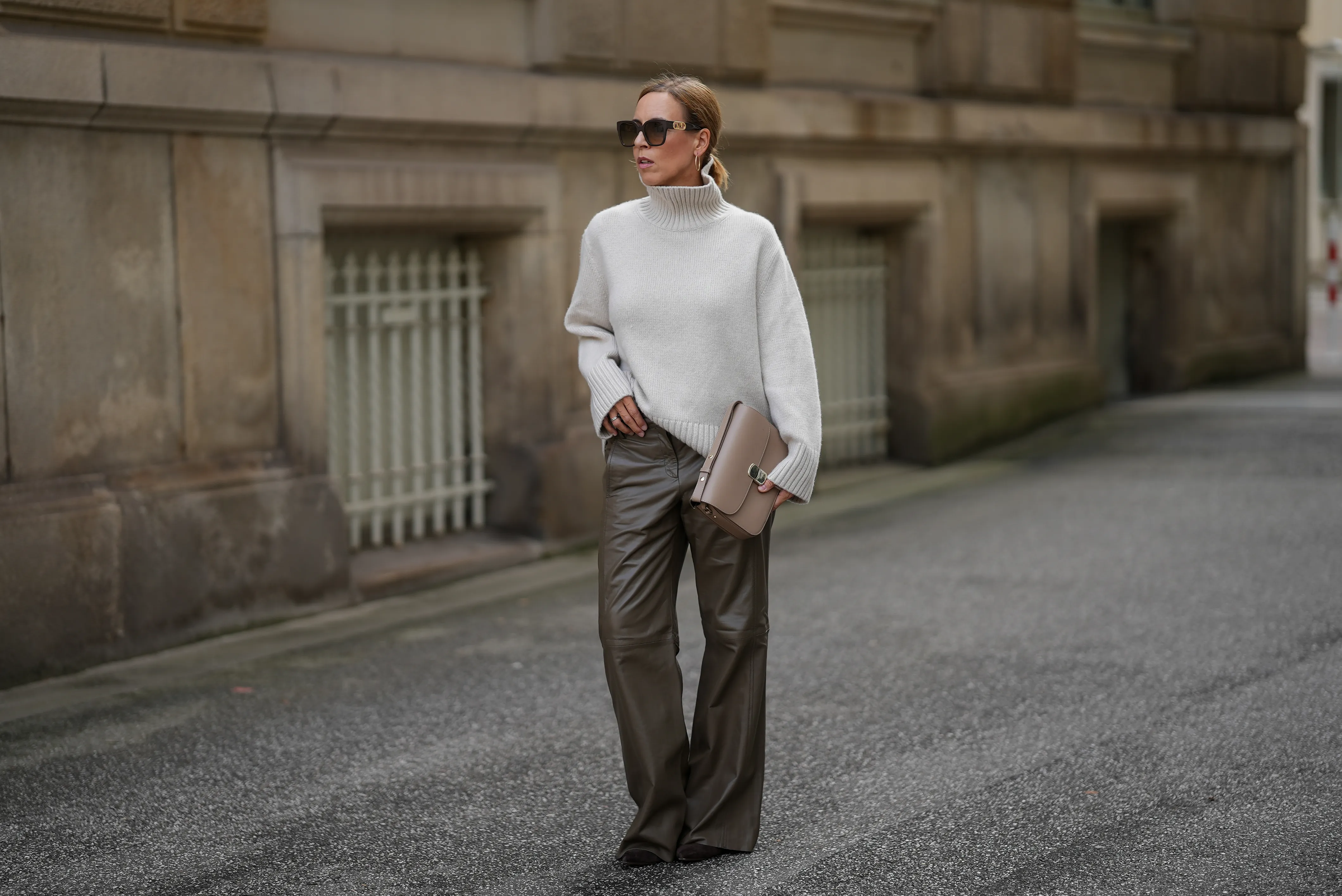 HAMBURG, GERMANY - SEPTEMBER 19: Alexandra Siedschlag is seen wearing a relaxed, high-collar ivory cashmere pullover with a soft ribbed texture from & Other Stories; khaki brown nappa sheepskin leather trousers with decorative stitching and wide leg silhouette from Bonprix; pointed dark brown suede boots with stiletto heel from Arket; a structured taupe leather Milo shoulder bag with gold hardware from S&eacute;zane; golden mid sized hoop earrings from Sence Copenhagen; oversized square sunglasses with acetate frame, golden logo detail on the temples and gradient glasses from Fendi; her blonde hair is styled in a sleek bob on September 19, 2025 in Hamburg, Germany. (Photo by Moritz Scholz/Getty Images)