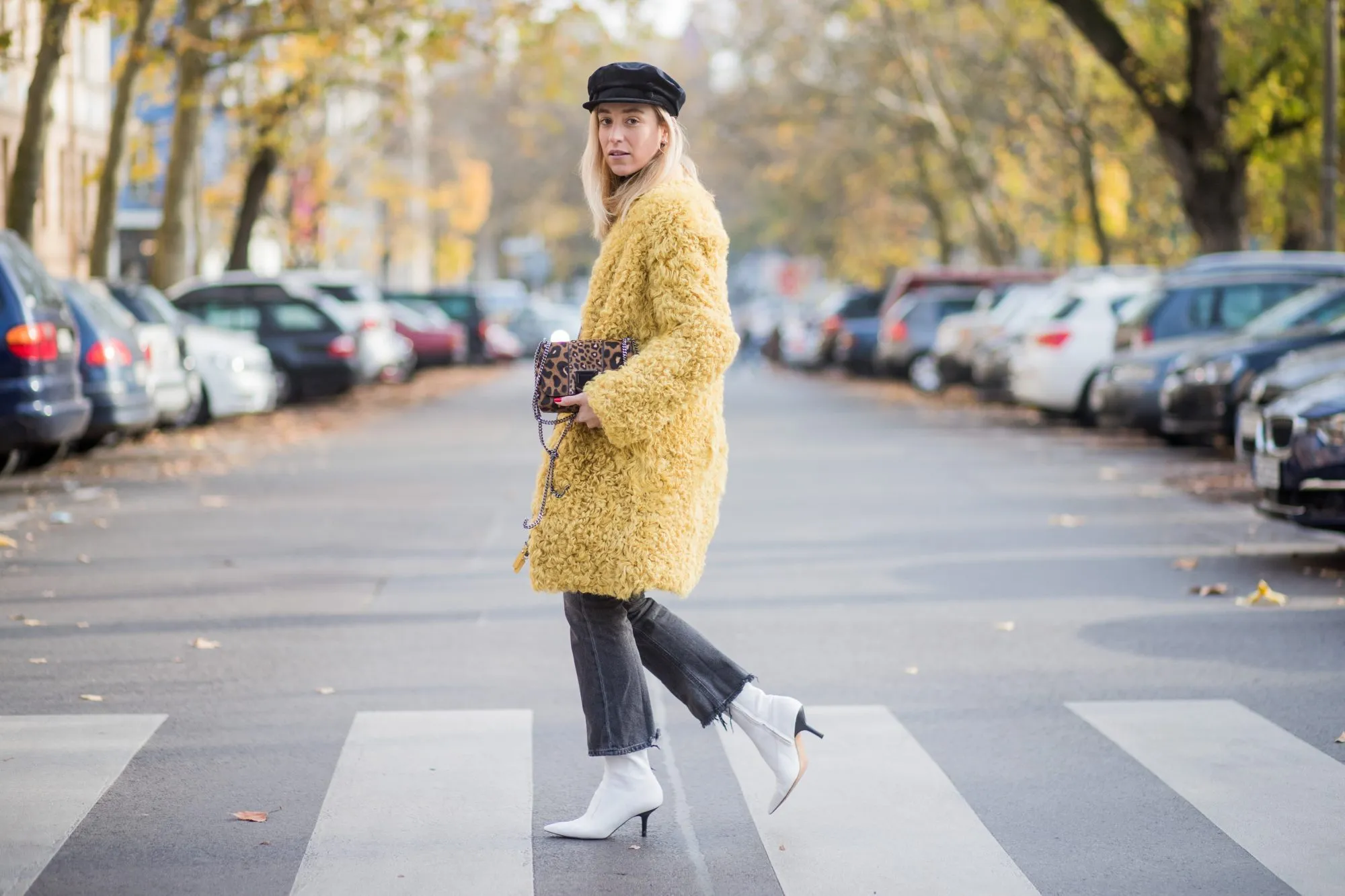 BERLIN, GERMANY - NOVEMBER 04: Sonia Lyson Jimmy Choo lockett petite bag hazelnut mix with leopard pony mix, shearling mustard coat Longchamp, black turtleneck & black Zara hat, dark grey skinny cropped flared jeans Citizens of Humanity, white H&M boots on November 4, 2017 in Berlin, Germany. (Photo by Christian Vierig/Getty Images)