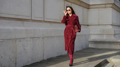 PARIS, FRANCE - DECEMBER 09: Patricia Gloria Contreras wears long straight dark brown hair worn loose, natural skin with neutral lipstick, dark tinted rectangular sunglasses by Bulgari, a burgundy long wool coat worn open by The Frankie Shop with a straight silhouette and wide lapels, burgundy opaque tights, pointed toe high heel pumps by Saint Laurent in black leather, and a burgundy quilted leather shoulder bag with a gold chain strap by Chanel, during a street style fashion photo session, on December 09, 2025 in Paris, France. (Photo by Edward Berthelot/Getty Images)